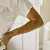 zelfliefde, witte t-shirt met hartje en woord "self" op, arm met een grote pigmentvlek op